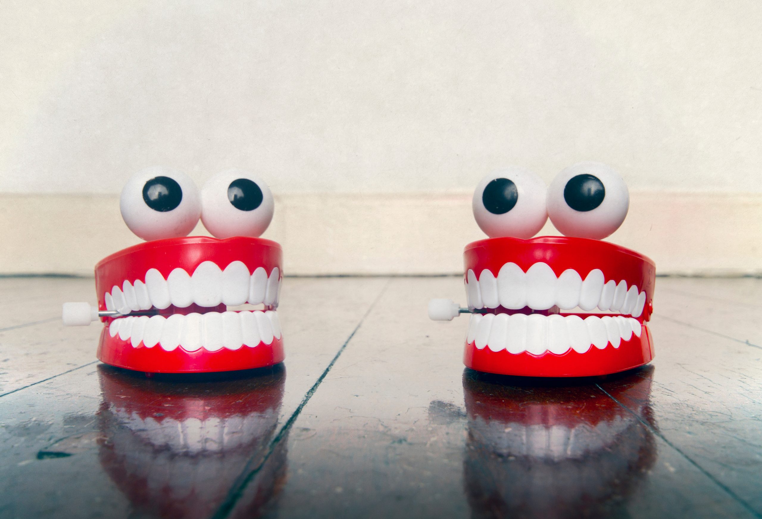 Two,Platic,Teeth,Toys,Chatting,On,A,Old,Wooden,Floor